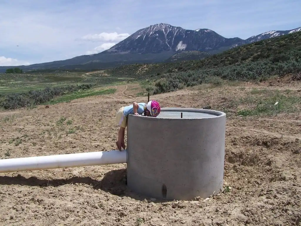 Concrete water tank with curved top and pipe connection.